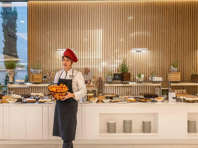Moderne Hotelbar mit langer Theke, vielen Flaschen und Gläsern, Barkeeper mit rotem Hut.