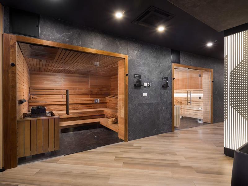 Moderne Sauna mit Glasfronten, dunklen Holzverkleidungen und heller Holzbodenfläche.