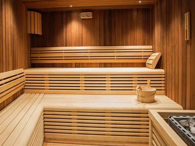 Sauna in legno con panche a più livelli e secchio con mestolo