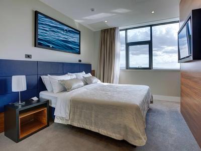 Camera d'hotel moderna con letto grande, accenti blu e opera d'arte con vista mare.