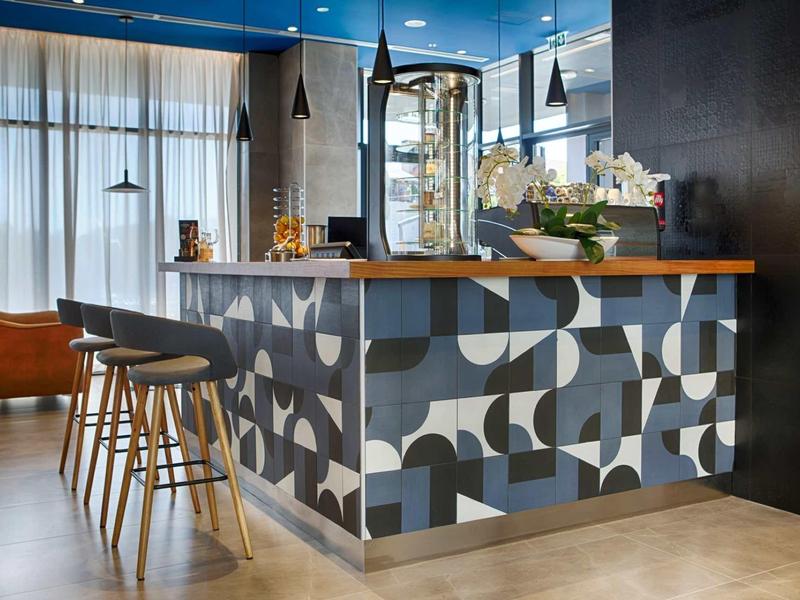 Area bar dell'hotel moderna con bancone decorato e sgabelli imbottiti.