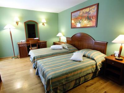 Hotelzimmer mit zwei Einzelbetten, Holzmöbeln und grünen Wänden