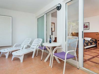 Heller Balkon mit zwei Liegestühlen, einem kleinen Tisch und Blick ins Wohnzimmer.