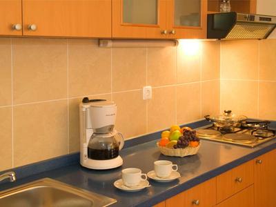 Moderne Küchenzeile mit Kaffeemaschine, Obstschale und Herd in warm beleuchtetem Raum.