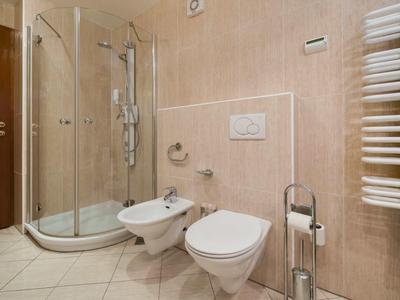 Modernes Badezimmer mit bodenebener Dusche, Wandtoilette und Bidet in beige Fliesen.