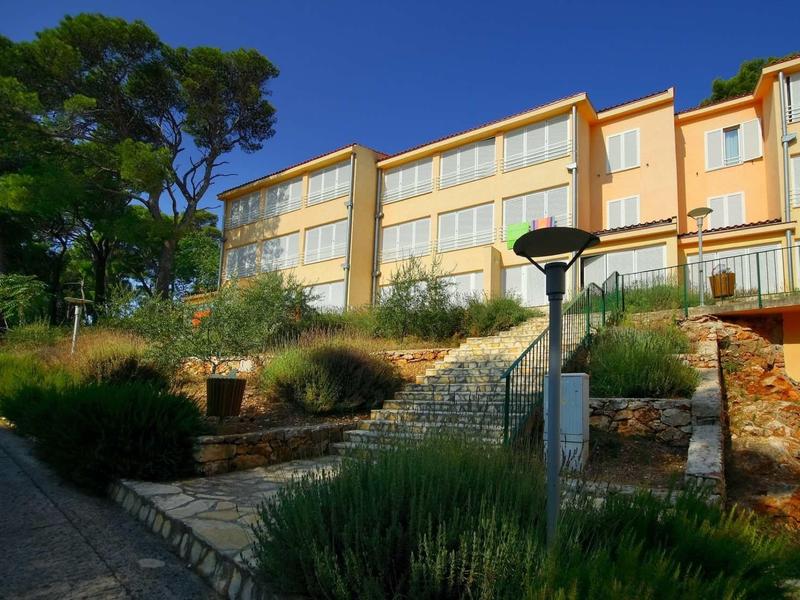 Meerlaagse hotelgebouw op een helling met trappen en omliggende begroeiing.