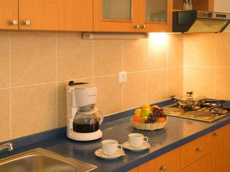 Moderne keukenlade met koffiemachine, fruitschaal en fornuis in warme verlichting.