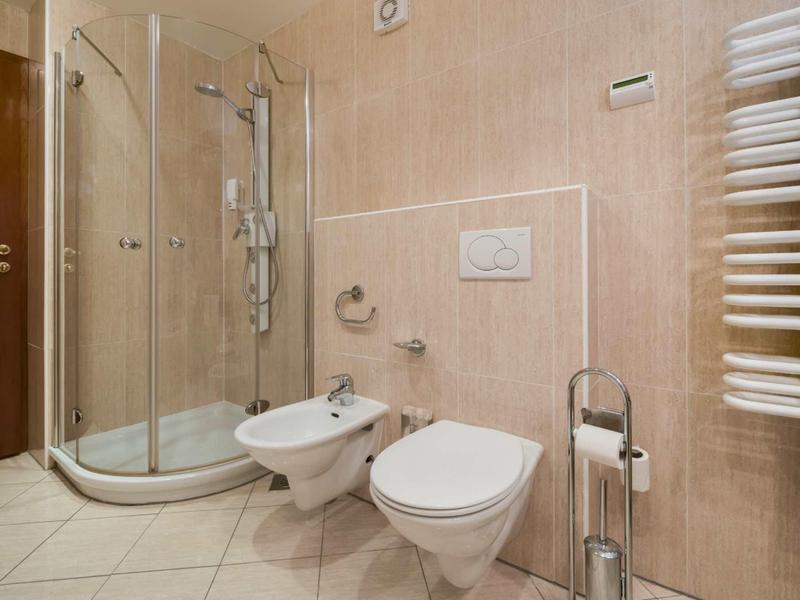 Moderne badkamer met douchecabine, hangend toilet, bidet en verwarmde handdoekrek.