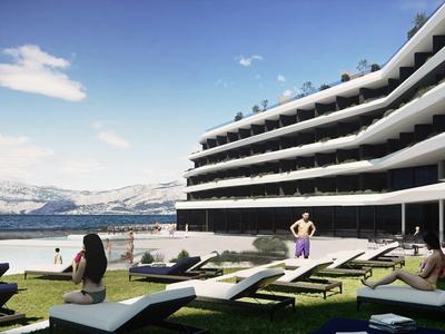 Modernes Hotel mit terrassenförmigen Balkonen, Liegestühlen und Blick auf einen See und Berge.