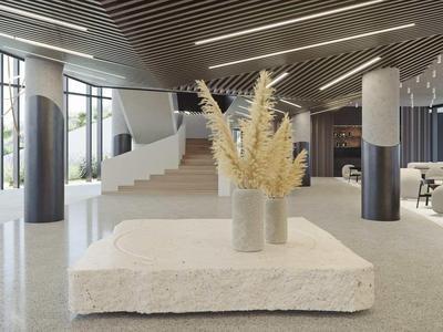 Luminoso vestíbulo de hotel con escalera moderna, grandes ventanales y plantas decorativas sobre la mesa.
