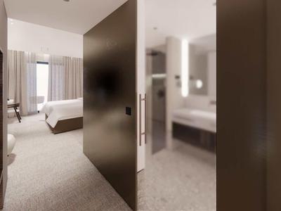 Modern hotel room area with open bathroom and large window