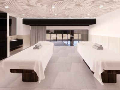 Habitación de spa moderna con dos camillas blancas y luz tenue.