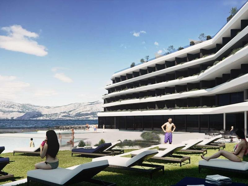 Modern hotel complex with terrace, lounge chairs, and view of lake and mountains.