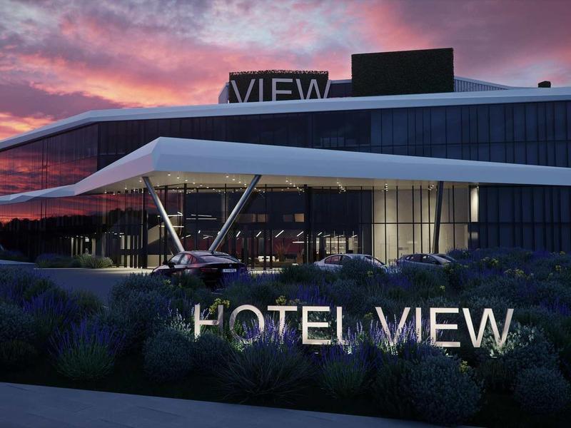 Modern hotel building at sunset with illuminated »HOTEL VIEW« sign.