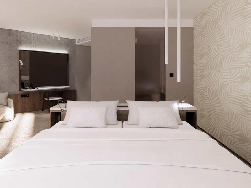 Modern hotel room with large bed, bright colors, and stylish decor.