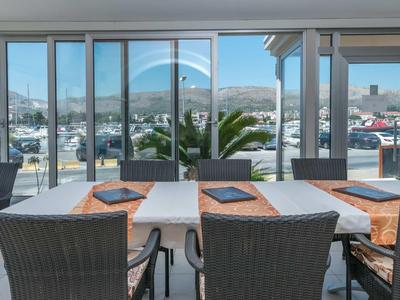 Moderner Außenbereich mit Holztisch, schwarzen Stühlen und großer Glasfront mit Bergblick.