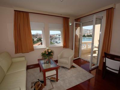Cozy living room with sofa, armchairs, table with flowers, and access to balcony with chairs.