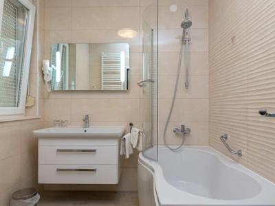 Modern bathroom with bathtub, sink, mirror, and window.