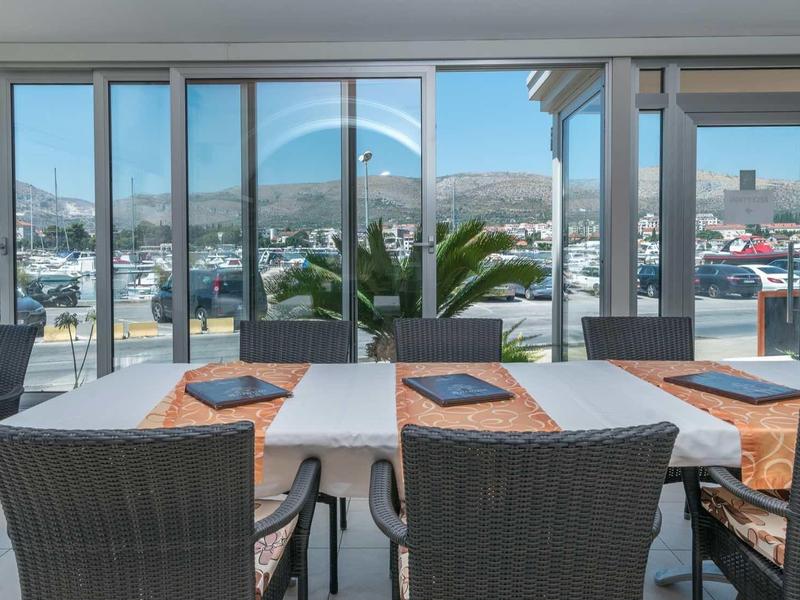 Coin repas moderne avec table et chaises, grandes fenêtres donnant sur la ville et les montagnes.