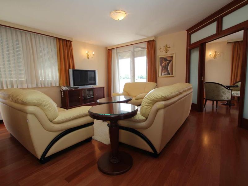 Espace de vie confortable avec deux canapés en cuir, sol en bois et téléviseur dans une chambre d'hôtel.