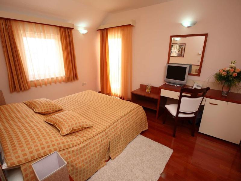 Chambre d'hôtel confortable avec lit double, bureau, chaise et minibar aux tons chauds.