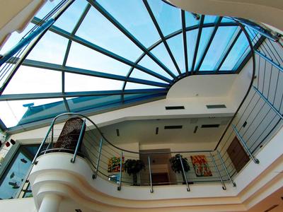 Vue vers le haut d'un hall d'hôtel moderne avec un toit en verre et des balcons autour.