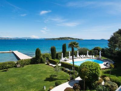 Giardino dell'hotel con piscina, lettini e vista mare sotto cielo azzurro