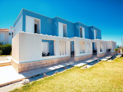 Modern twee-onder-een-kapwoning met terras en tuin onder een heldere blauwe lucht.