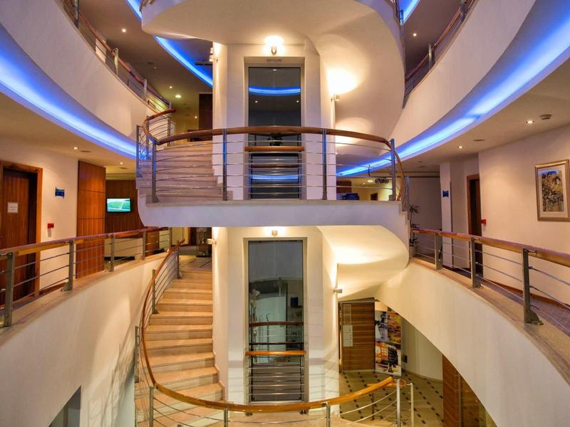 Schody spiralne w centrum nowoczesnego wnętrza hotelu z ciepłym oświetleniem.