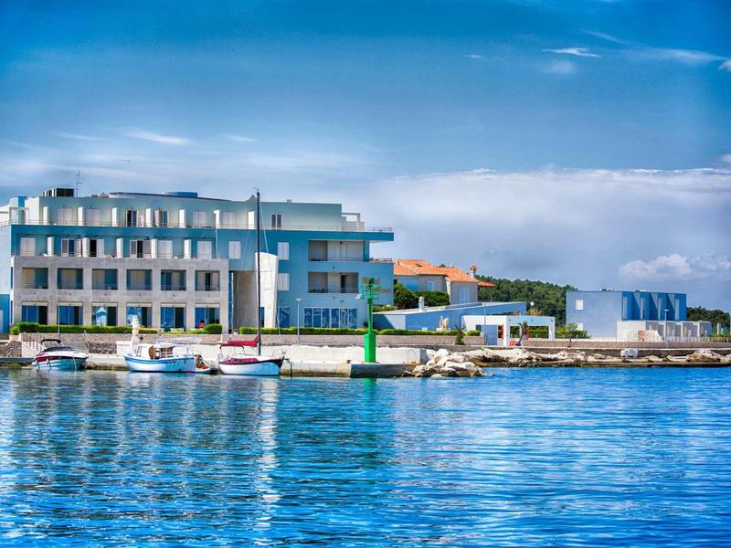 Nowoczesny hotel nad spokojną wodą z czystym niebem i zacumowanymi łodziami.