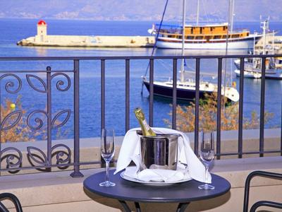 Tavolo sul balcone con champagne, secchio refrigerante e vista sul porto e mare sotto un cielo limpido.
