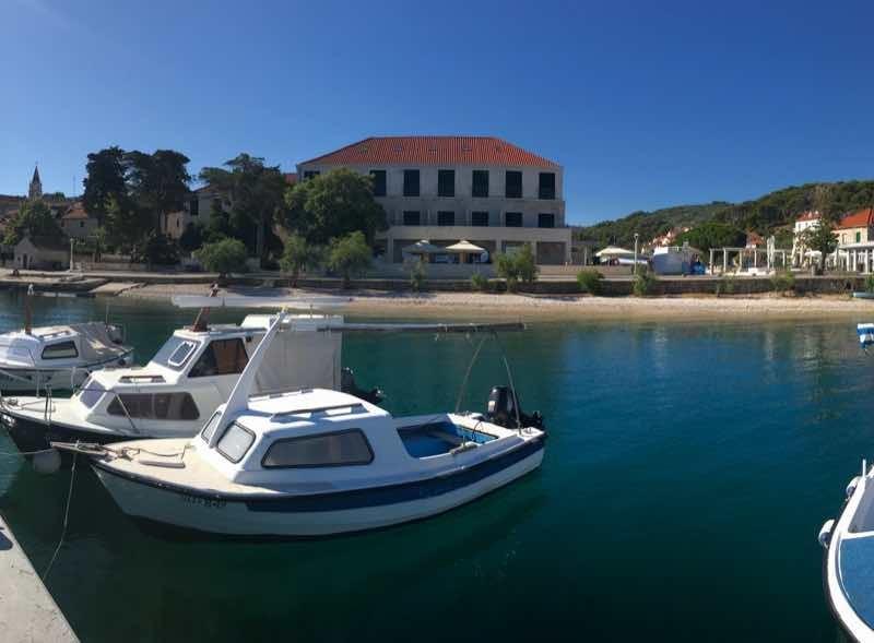 Panoramisch uitzicht op een haven met boten en gebouwen langs de kust bij een heldere lucht.