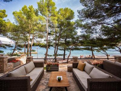 Accogliente terrazza con divani con vista sul mare e alberi sulla spiaggia.