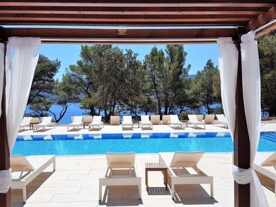 Bazénová oblast s lehátky a výhledem na moře pod zastřešenou terasou.