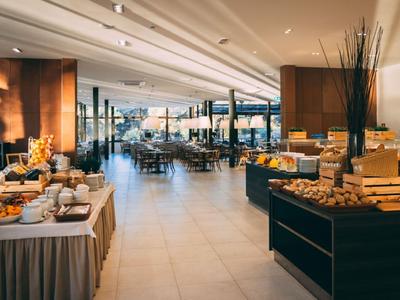 Ein eleganter Frühstücksraum mit Buffet und Blick auf die Stadt durch große Fenster.