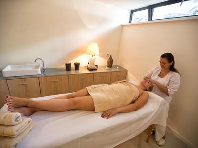 Žena dostává ošetření obličeje v světlé hotelové wellness místnosti.