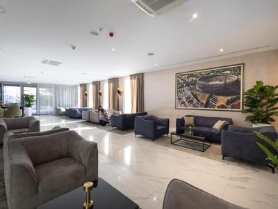 Moderner Hotel-Lobby-Bereich mit grauen Sesseln, Sofas und großen Fenstern.