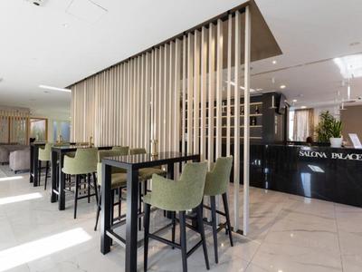 Moderner Hotel-Lounge-Bereich mit hohen Tischen, grünen Stühlen und Empfangstresen.