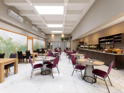 Moderner Frühstücksraum mit Tischen, Stühlen und Buffet in einem Hotel.