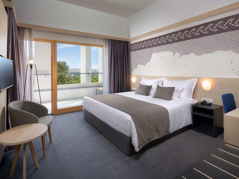 Modernes Hotelzimmer mit Doppelbett, Balkon und Panoramafenster.