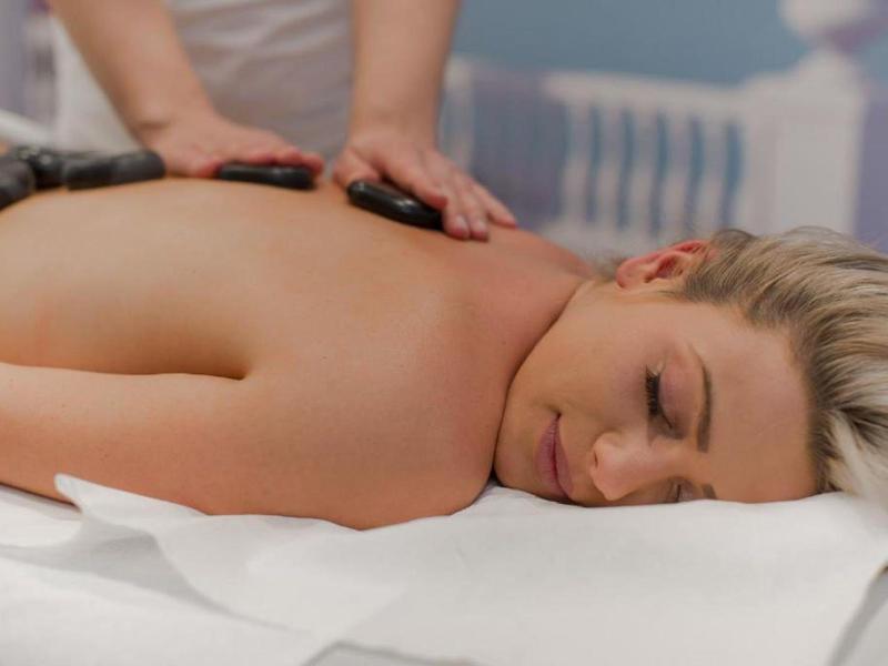 Frau entspannt während einer Hot-Stone-Massage auf einer Massagebank.
