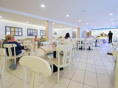Bright, modern restaurant with white chairs, tables, and tiled floors.