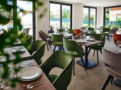 Modern dining area with green and beige chairs, set tables, and large windows.