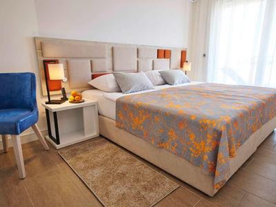 Modern hotel room with large bed, nightstand, chairs, and bright window