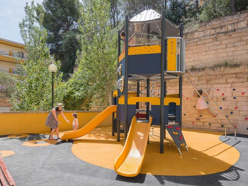 Een moderne speeltuin met glijbaan, klimnet en speeltoren in een stedelijke omgeving.
