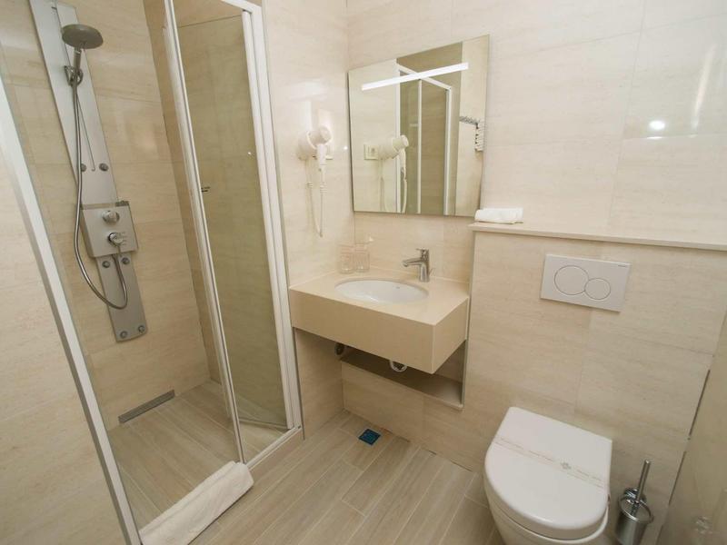 Helles Badezimmer mit Duschkabine, Wandwaschbecken, Spiegel und wandhängendem WC.