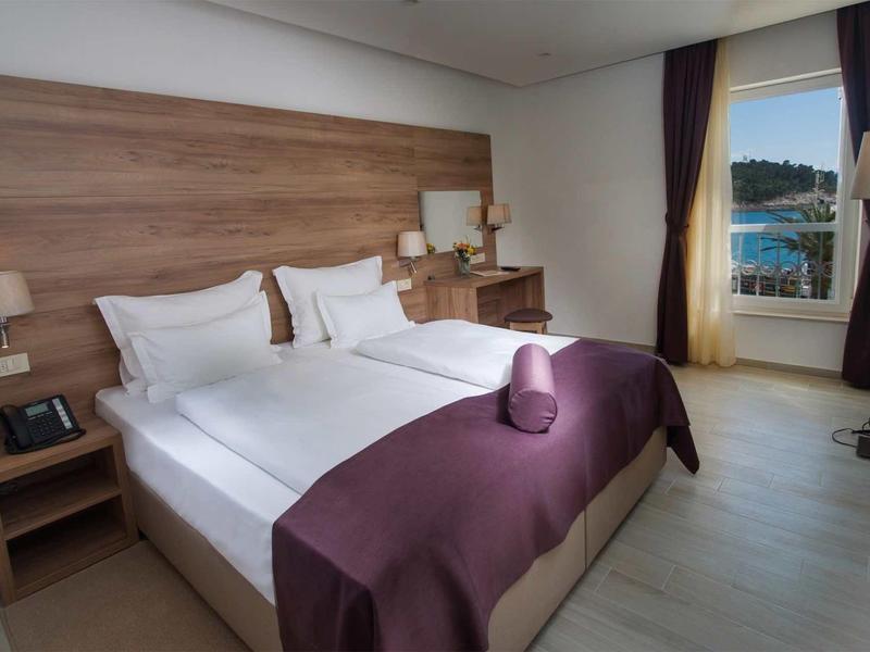 Modernes Schlafzimmer mit Doppelbett, weißen Wänden, Holzakzenten und Fenster mit Ausblick.