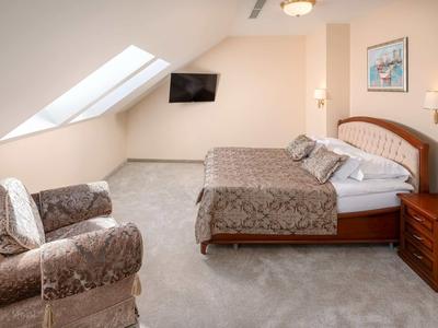 Przytulny pokój hotelowy z dwoma łóżkami pojedynczymi, fotelami i oknem dachowym.