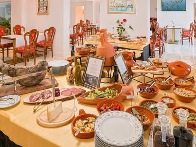 Bufet z różnymi miskami i talerzami w jasnej jadalni z drewnianymi stołami.