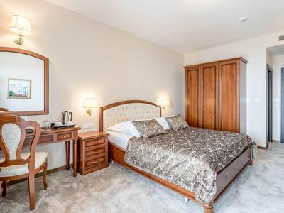 Jasny pokój hotelowy z podwójnym łóżkiem, drewnianymi meblami, biurkiem i wykładziną.